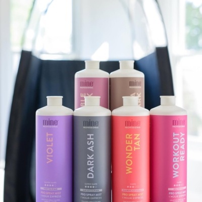 Frascos coloridos de produtos Mine Professional para spray mist em várias cores sobre uma mesa.