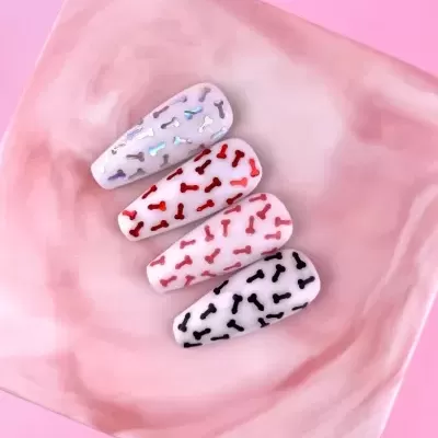 Unhas postiças com desenhos pequenos em forma de ossos coloridos sobre fundo branco