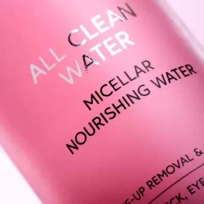 Garrafa rosa com texto branco e preto sobre água micelar