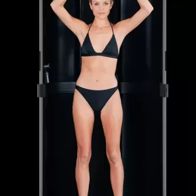 Mulher de biquíni preto dentro de cabine de bronzeamento preta