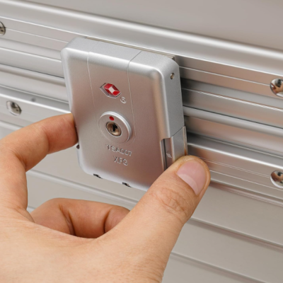 Fecho de mala prateado com símbolo vermelho e escrita TSA007 XFS