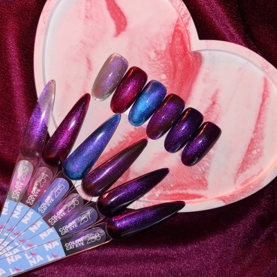 Amostras de unhas falsas com efeito cat eye em vários tons roxos e azuis sobre prato em forma de coração marmoreado.