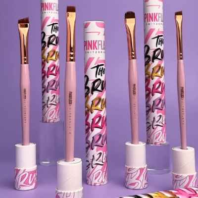 Pincéis de maquilhagem rosados com embalagens cilíndricas coloridas e texto visível em fundo lilás