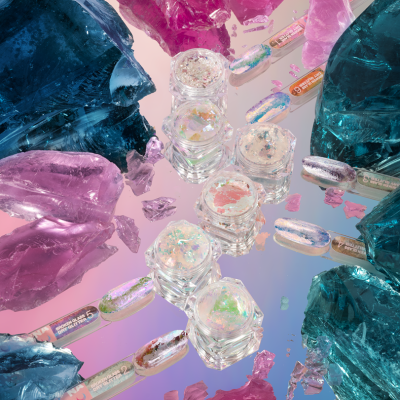 Potes pequenos com glitter iridescente e pedaços de vidro colorido em azul, rosa e roxo.