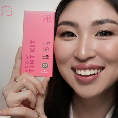 Mulher segurando embalagem rosa de kit de tintura para sobrancelhas