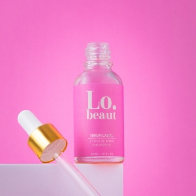 Frasco de sérum labial com conta-gotas em fundo rosa