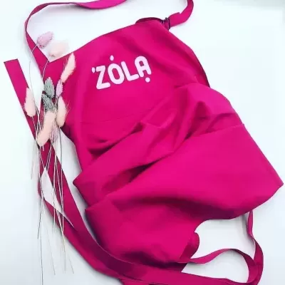 Avental rosa com inscrição ZOLA e raminhos decorativos ao lado
