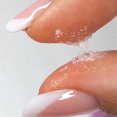 Dedos femininos com unhas francesinhas segurando gel transparente