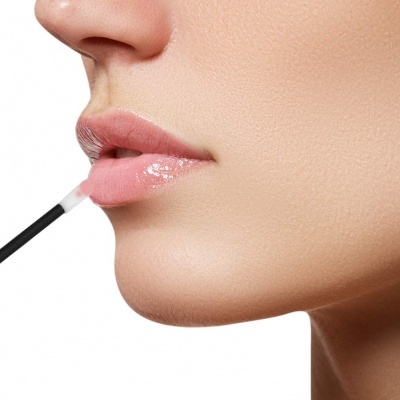 Mulher aplicando gloss labial transparente nos lábios