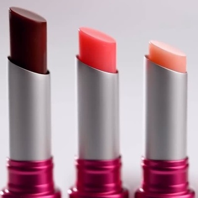 Três batons da marca Zõla em embalagens rosa, com cores castanho, rosa e rosa claro.