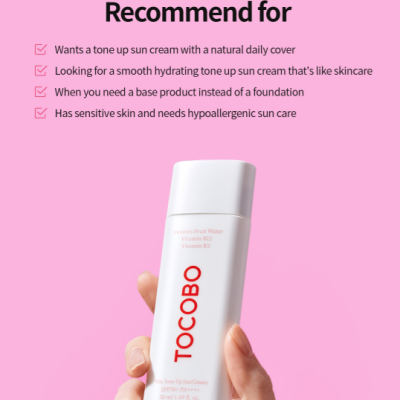 Frasco branco de protetor solar TOCOBO segurado por uma mão, fundo rosa com texto.