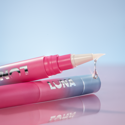 Duas canetas cosméticas rosa e azul, uma com gota transparente saindo da ponta aplicadora