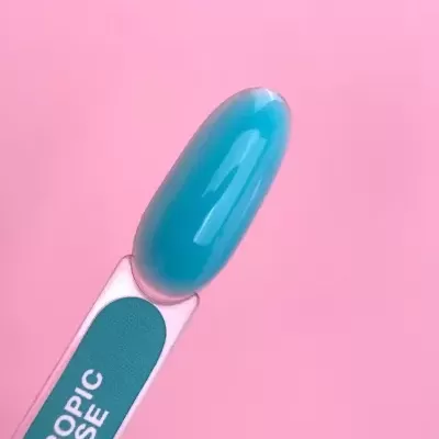 Pincel de verniz azul turquesa com rótulo 'TROPIC BASE' em fundo rosa