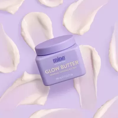 Frasco lilás de Glow Butter com manchas de creme lilás ao redor