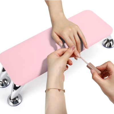 Almofada rosa para manicure com base cromada e mãos aplicando verniz