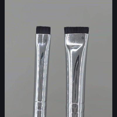 Dois pincéis de maquilhagem com cabo branco e cerdas pretas num fundo cinzento