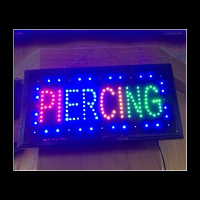 Sinal luminoso LED com a palavra PIERCING em cores variadas