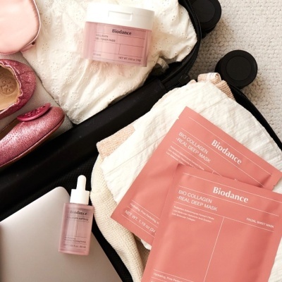 Produtos de beleza Biodance e roupas dentro de uma mala aberta.