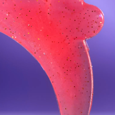 Objeto rosa translúcido com glitter sobre fundo azul e roxo