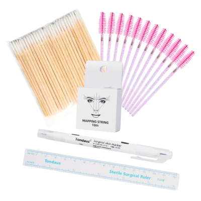 Produtos para maquilhagem e cuidados de beleza sobre fundo branco, incluindo escovas aplicadoras rosa, palitos de madeira, fio mapeamento, marcador de pele e régua cirúrgica.