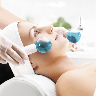 Mulher com esferas de vidro azuis no rosto em tratamento facial