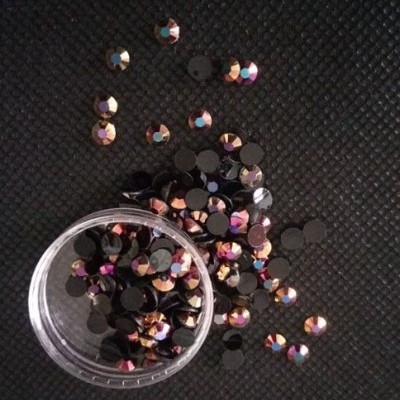 pedras decorativas redondas facetadas em recipiente plástico sobre tecido preto