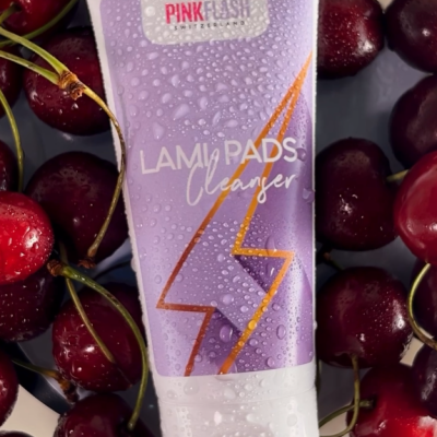 Tubete roxo de produto LAMI PADS Cleanser da PINKFLASH sobre cerejas vermelhas