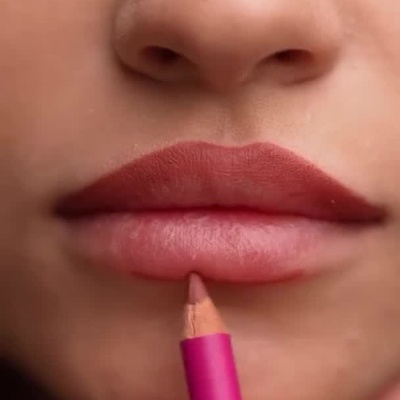 Lápis de lábios cor-de-rosa aplicado nos lábios de mulher