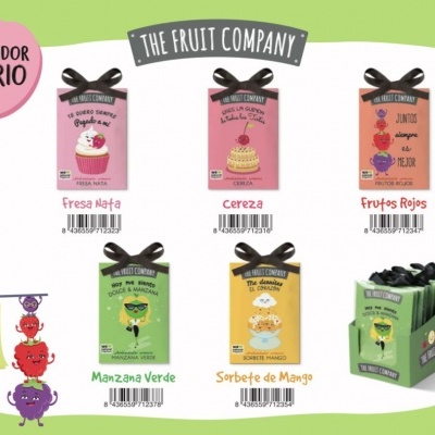 Seis ambientadores coloridos para armário com laço preto em embalagem pequena, apresentados num expositor verde.