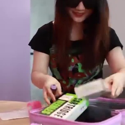 Mulher guarda produtos numa mala cor-de-rosa num ambiente lilás com texto