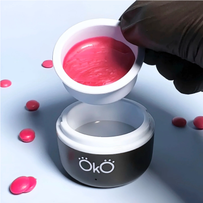 Frasco preto e branco com creme cor-de-rosa e gotas ao redor