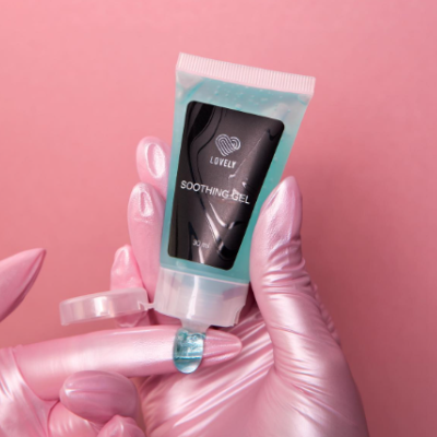 Tubo de gel calmante azul claro com rótulo preto em mãos com luvas cor de rosa