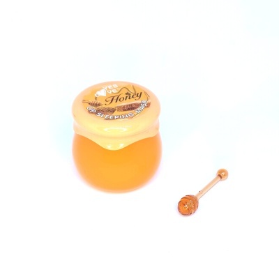 Frasco pequeno de mel com colher pequena de madeira