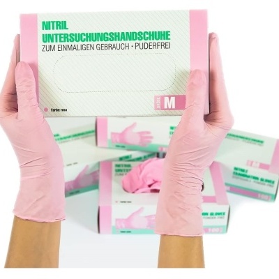 Caixa de luvas de exame de nitrilo tamanho M a ser segurada por mãos com luvas rosa, várias caixas ao fundo
