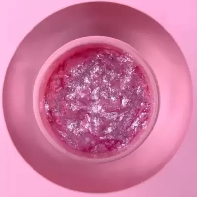 Creme cor-de-rosa brilhante num pote redondo sobre superfície rosa