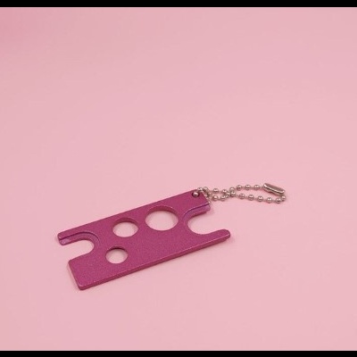 Chaveiro rosa com buracos circulares sobre fundo rosa