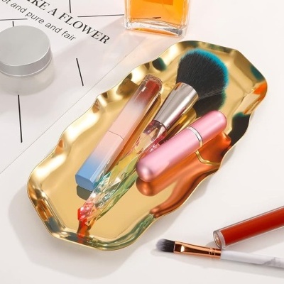 Bandeja dourada com pincel de maquilhagem, baton líquido e aplicador cor-de-rosa