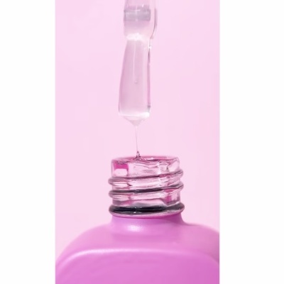 Frasco rosa com conta-gotas e líquido a pingar