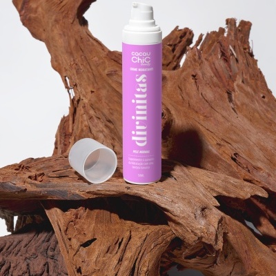 Frasco de creme hidratante roxo com tampa removida sobre madeira rústica