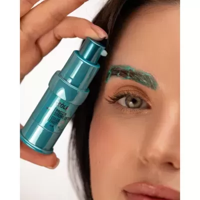 Recipiente azul metálico de produto para sobrancelhas e mulher aplicando na sobrancelha com produto verde