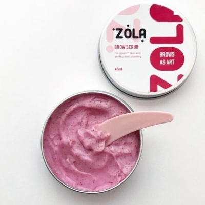 Zola Brow Scrub em embalagem redonda metálica com esfoliante rosa e espátula cor-de-rosa