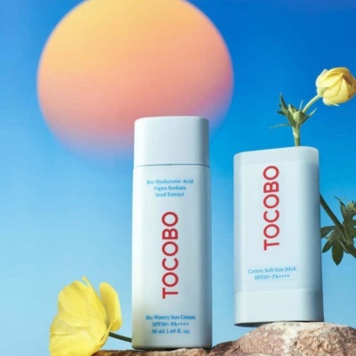 Dois produtos TOCOBO creme e stick solar com flores amarelas e fundo azul e laranja