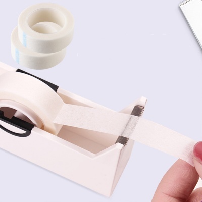 Fita adesiva branca em dispensador rosa claro com rolos extras ao fundo