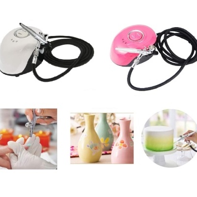 Dois aerógrafos com mangueiras, um branco e outro rosa, usados em unhas, cerâmica e pastelaria