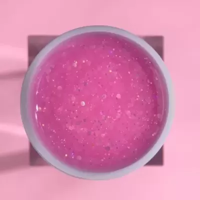 Pote com gel rosa translúcido com glitter sobre fundo rosa