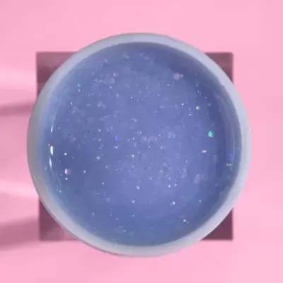 Pote com gel azul brilhante sobre fundo rosa
