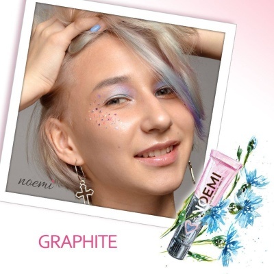 Mulher com maquilhagem azul e brilhantes na face, cabelo loiro com reflexos lilás, e embalagem de creme NOEMI rosa com flores azuis