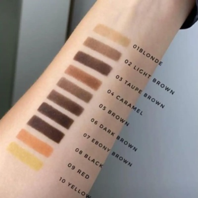 Amostras de maquilhagem em tons castanhos, vermelho e amarelo no braço com textos identificativos.