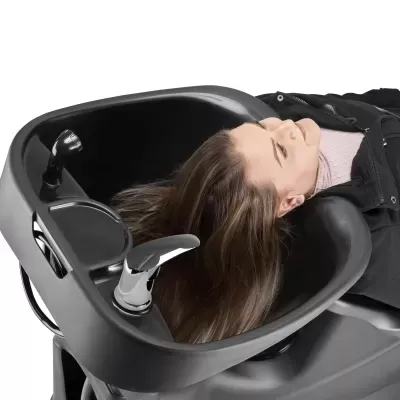 Lavatório de cabeleireiro preto com mulher deitada e cabelo castanho molhado