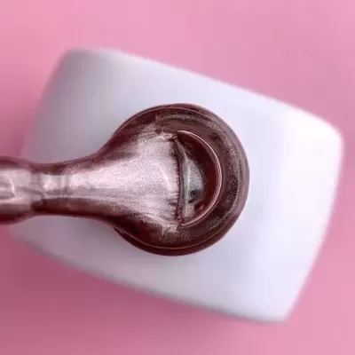 Pincel de verniz de unhas metálico castanho rosado com frasco branco sobre fundo rosa